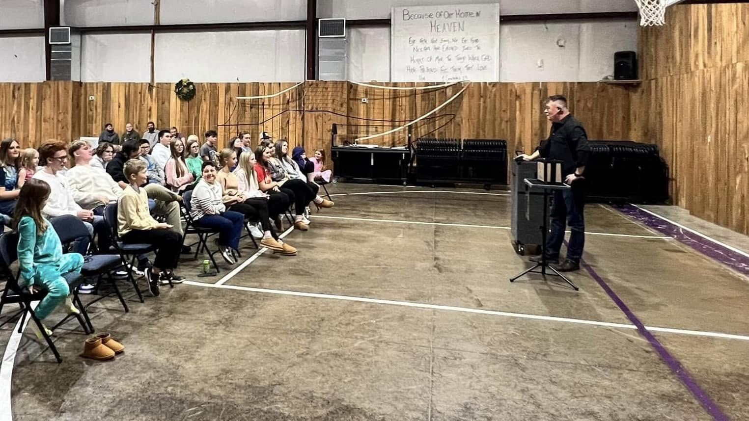 A seated audience watching Chris perform in a church gym