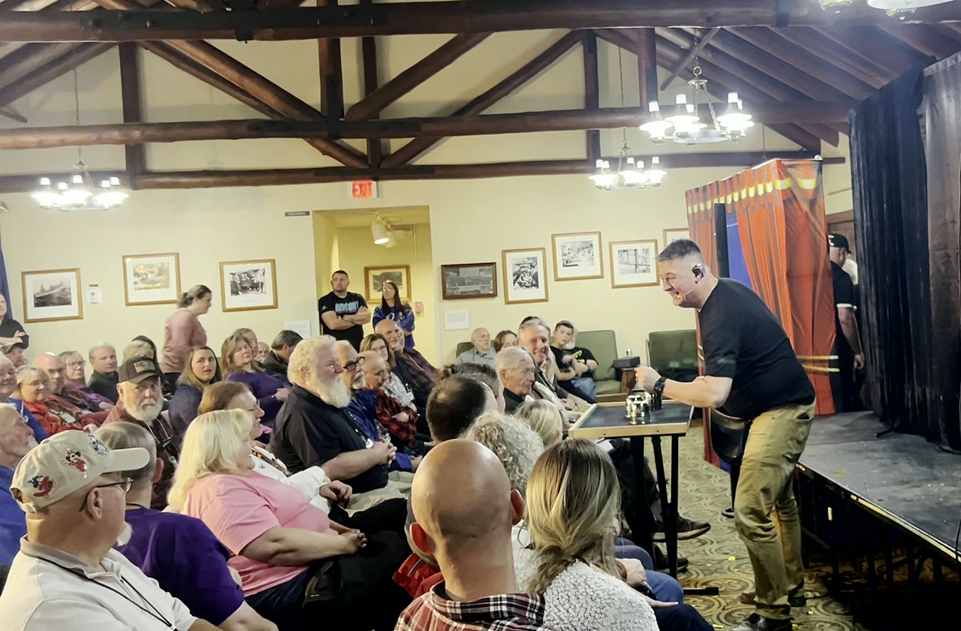 Chris Meece performing close-up magic for a packed room of adults