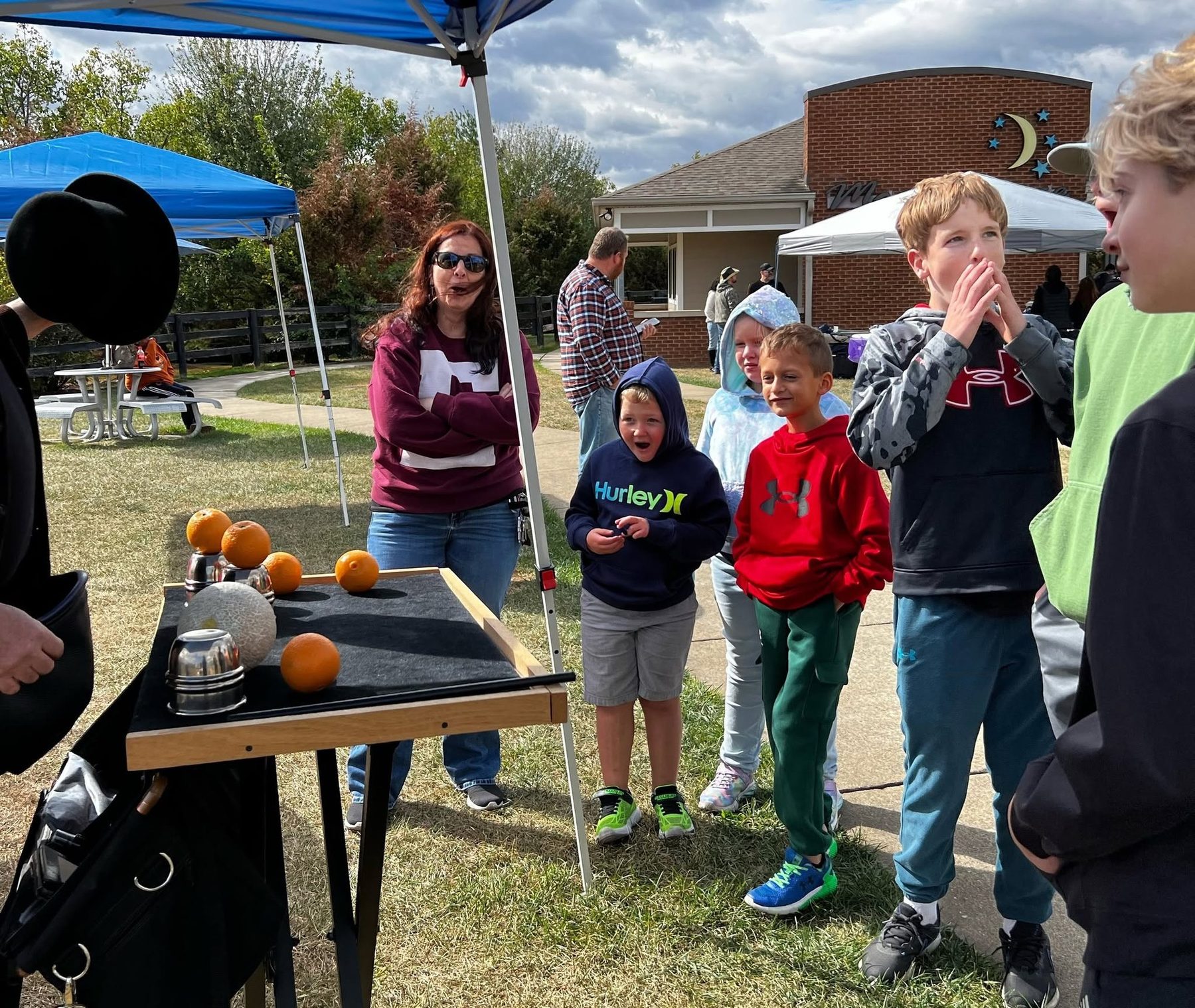 Children reacting to close-up magic at an outdoor event
