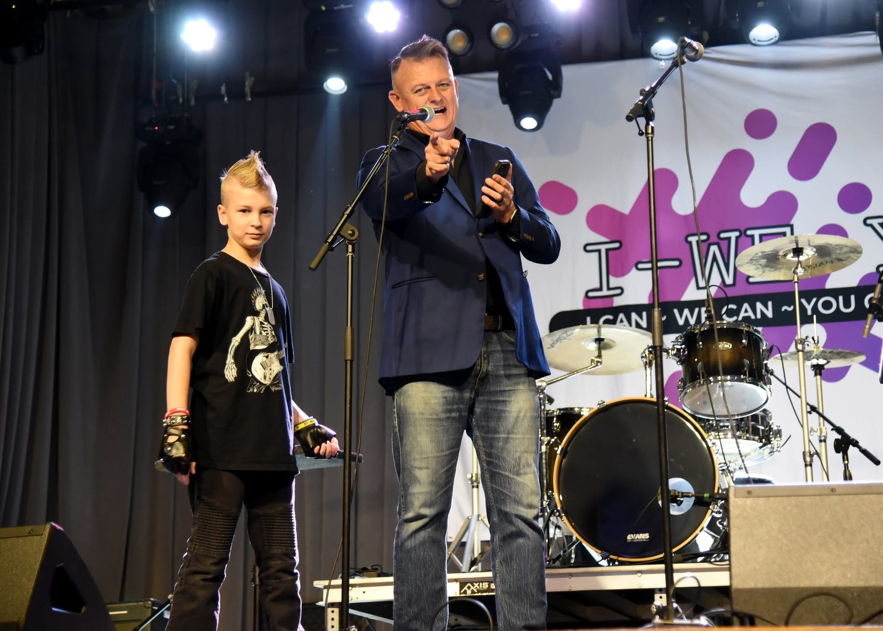 Chris Meece performing on stage with a young audience volunteer