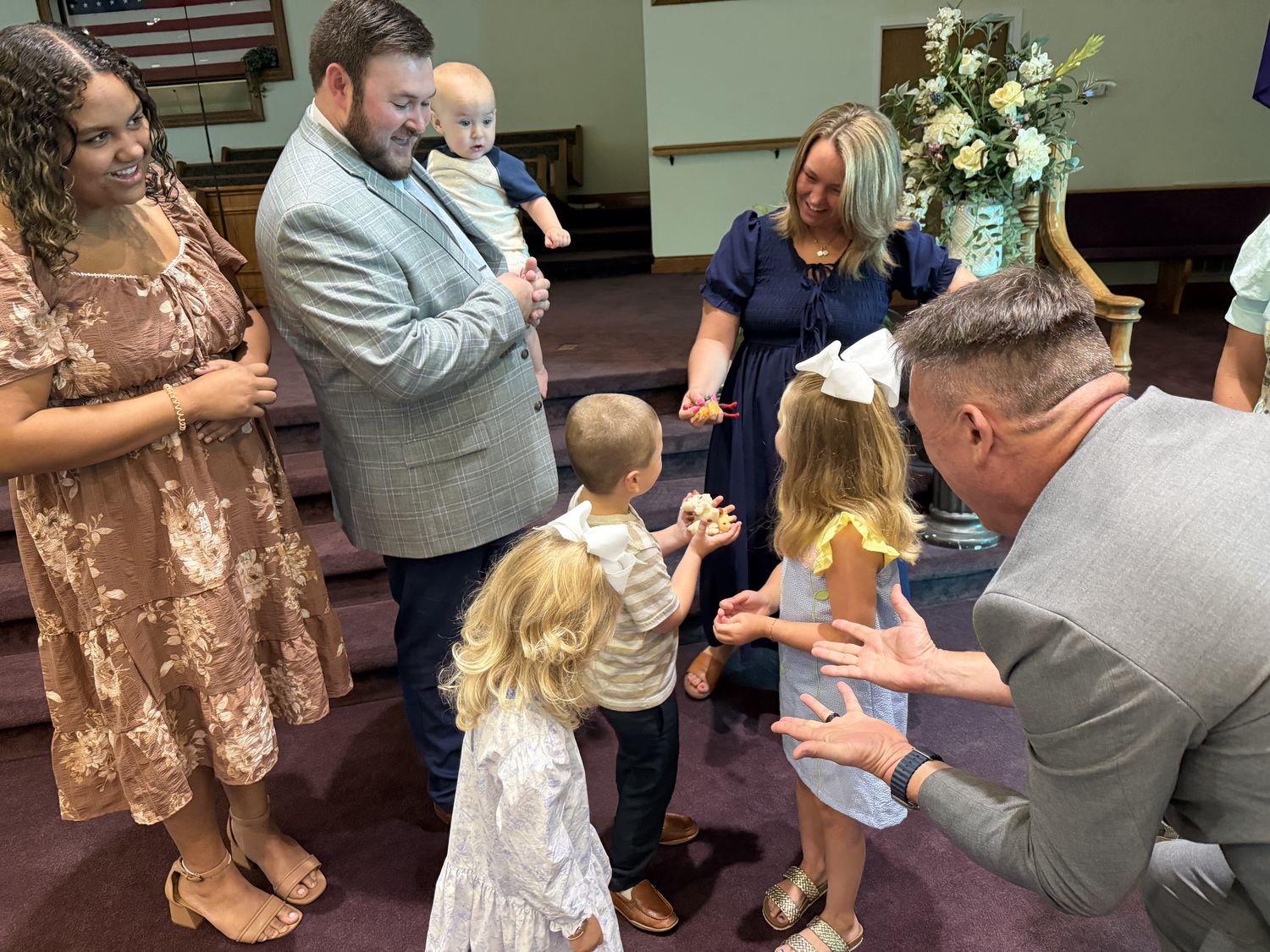 Guests of all ages laughing as Chris performs close-up magic at a wedding reception